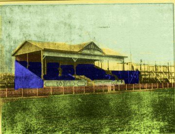 an old photo of a blue and white building next to the water in front of a fence