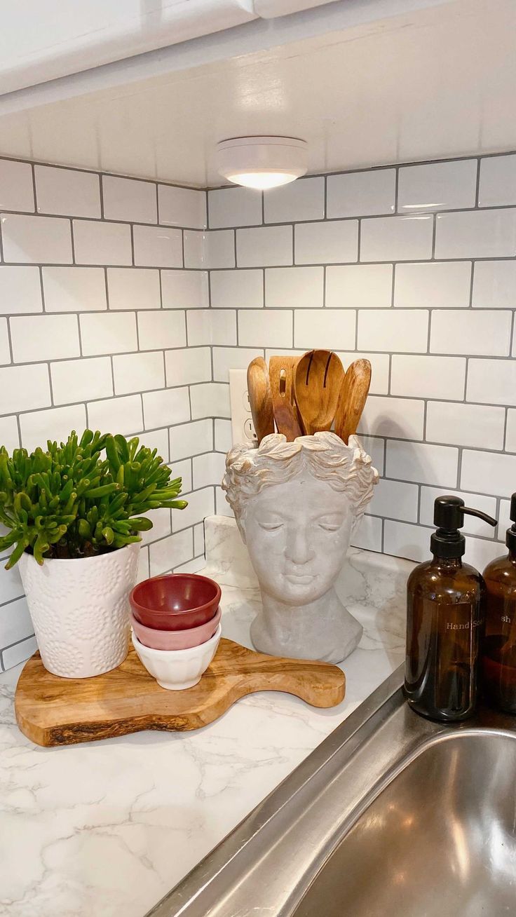 a kitchen sink with wooden utensils and a bowl on the counter next to it