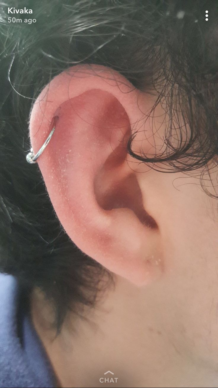 a person with black hair wearing a silver ear piercing on their left side of the ear