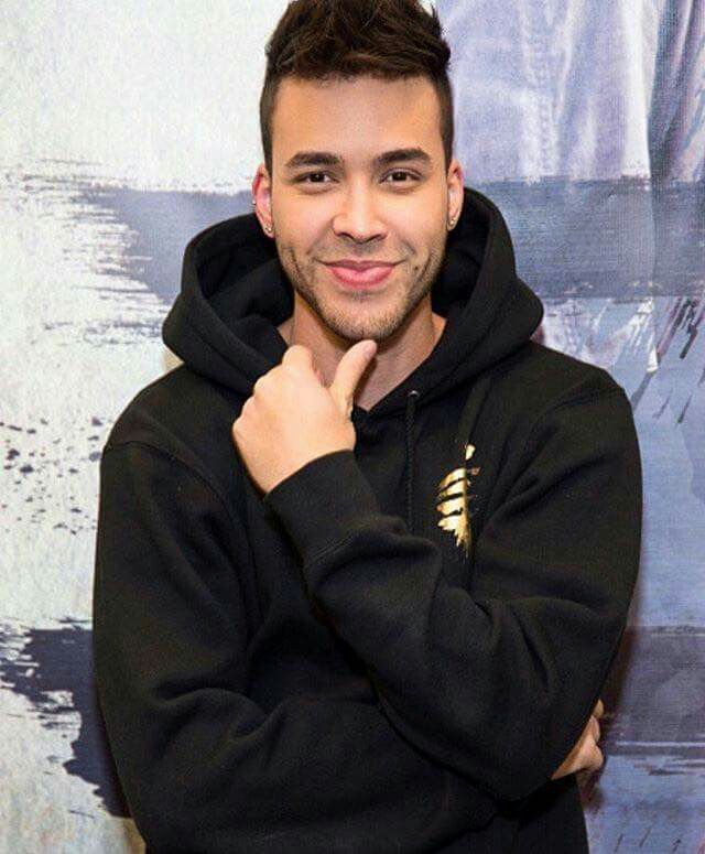 a man in a black hoodie posing for the camera with his hand on his chin