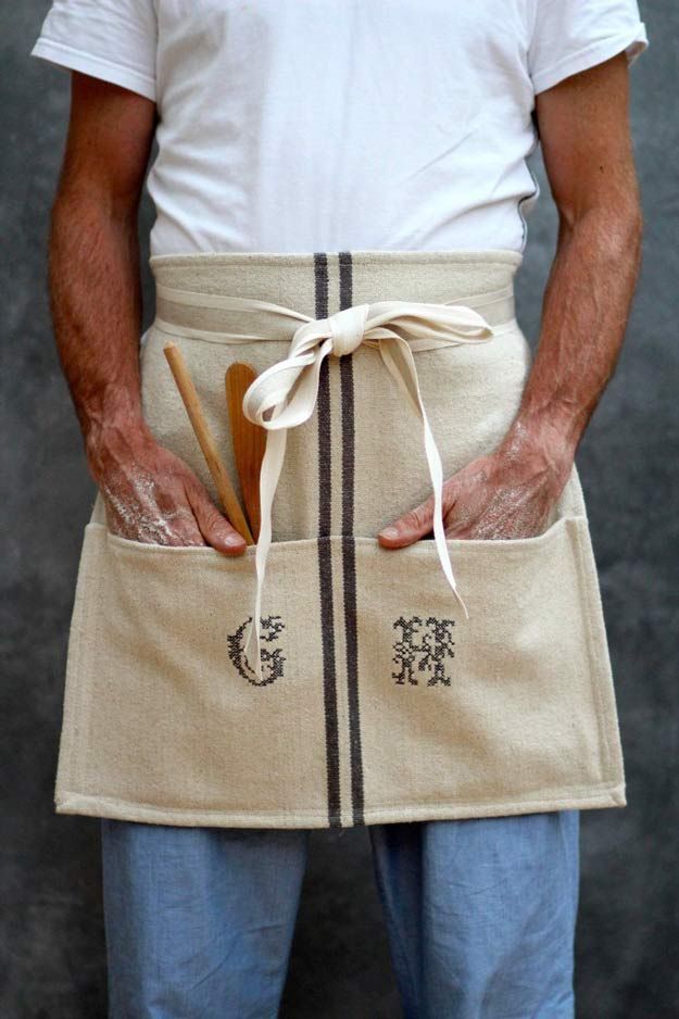 a man is wearing an apron and holding a wooden spoon in his pocket with both hands