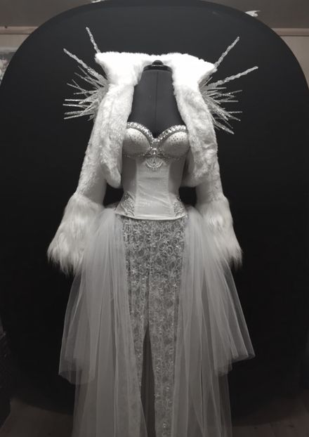 a mannequin dressed in white and silver with fur on it's head