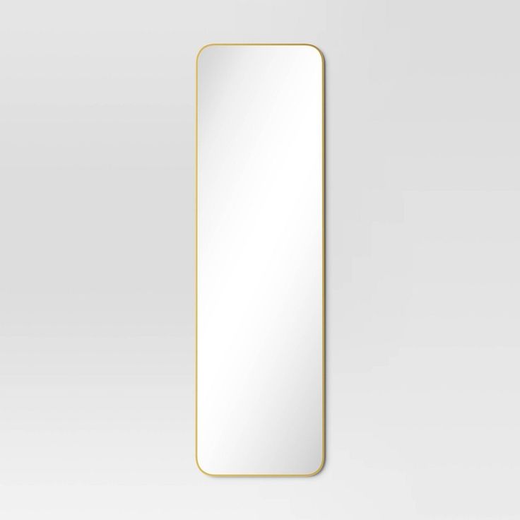 a rectangular mirror with a gold frame on a white wall, it is reflecting the light