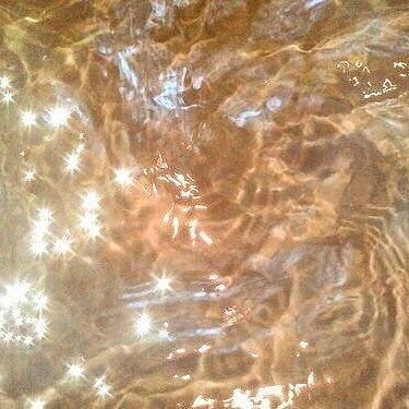 an image of water with stars in the middle and light reflecting off it's surface