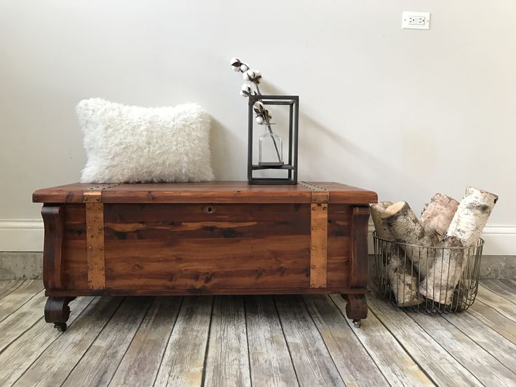 a wooden trunk sitting on top of a hard wood floor next to a white wall