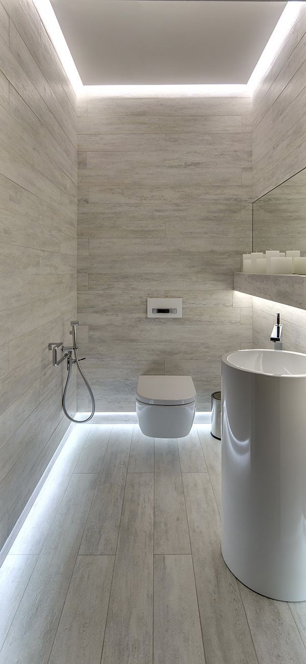 a bathroom with white walls and flooring, lights on the ceiling above the toilet