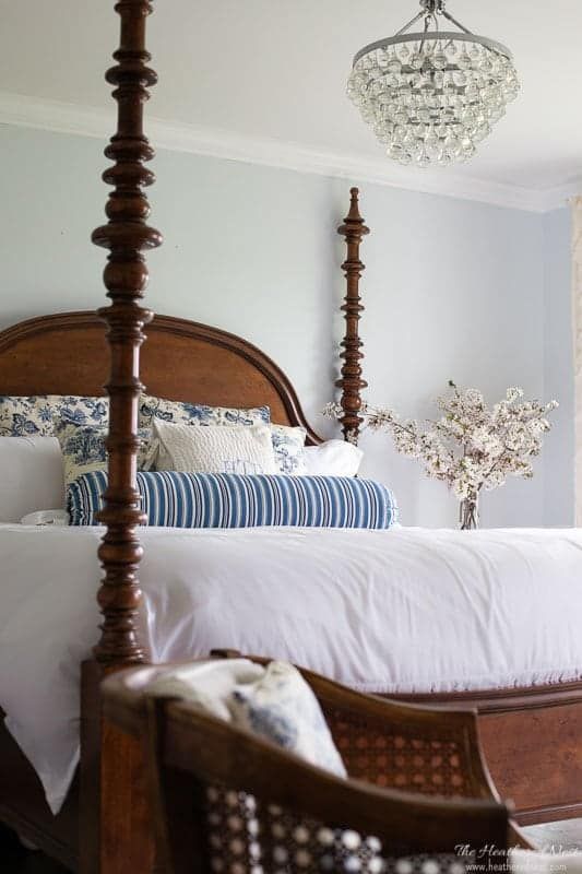 a bedroom with a four post bed and chandelier