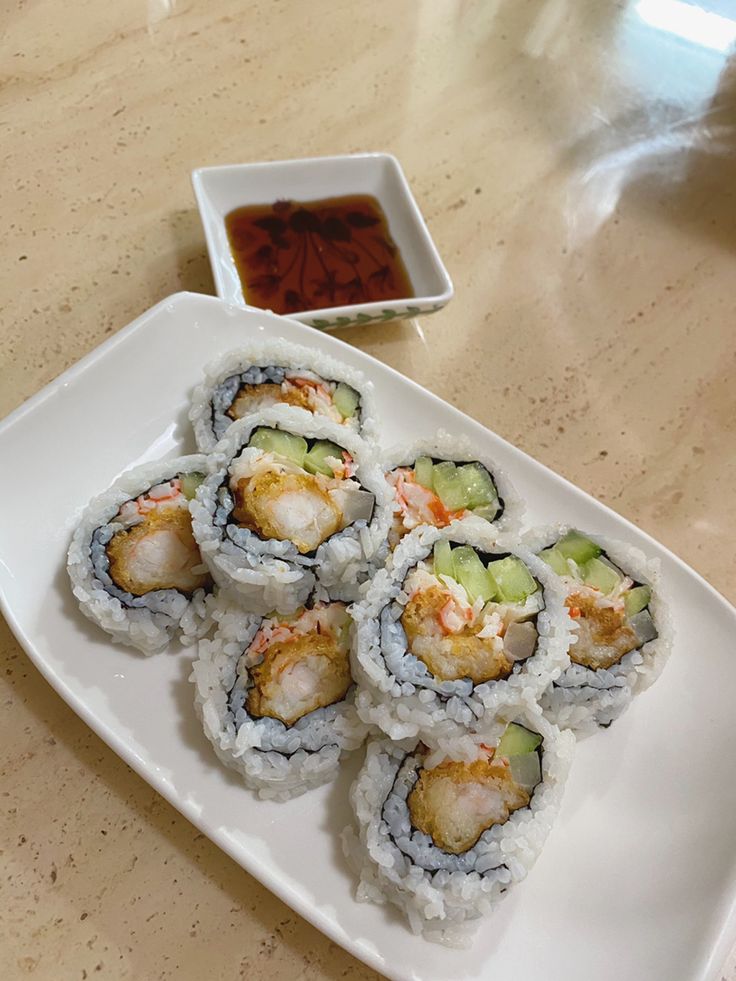 several sushi rolls on a white plate with dipping sauce