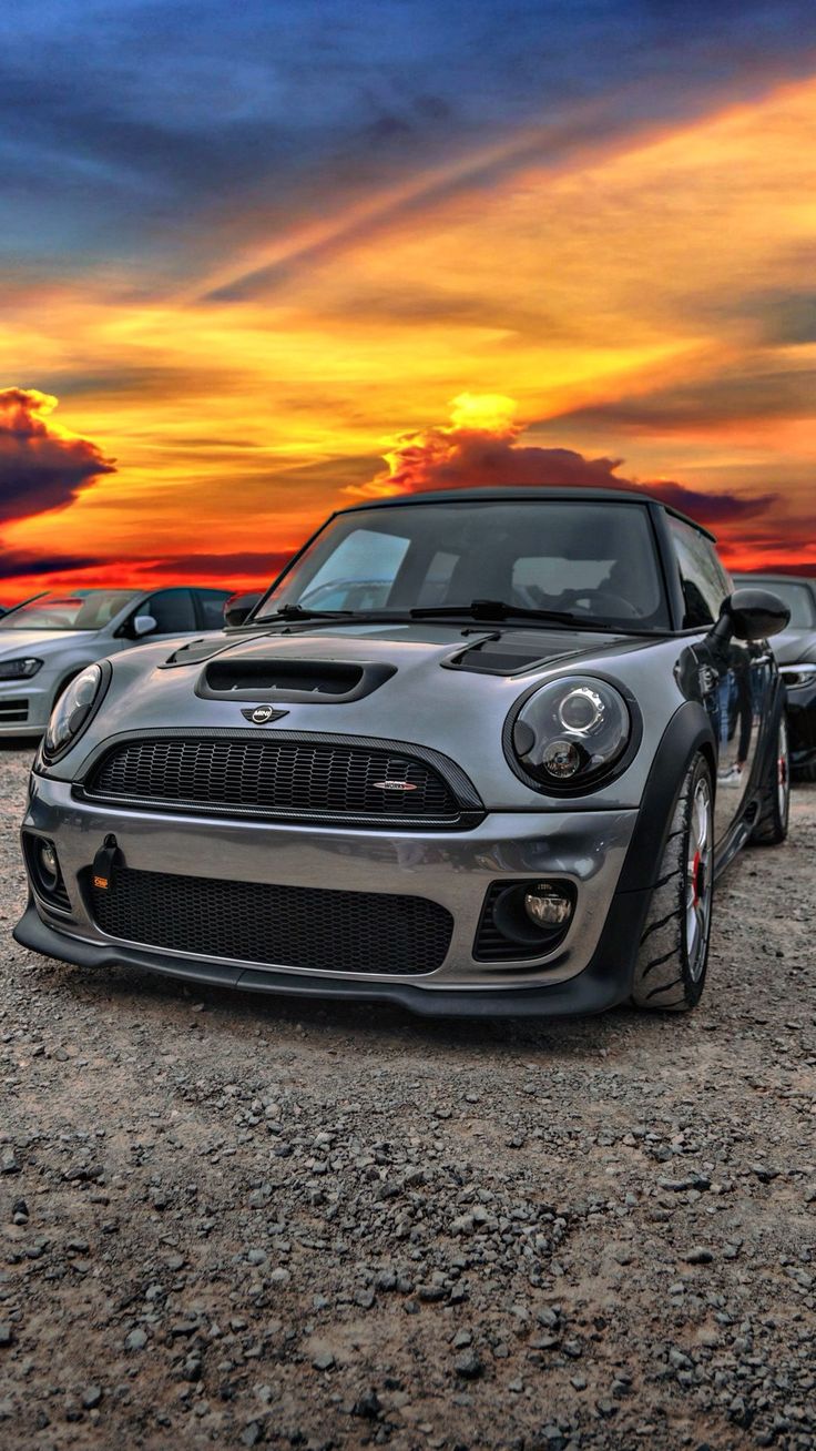 the front end of a car parked on top of a dirt field next to other cars