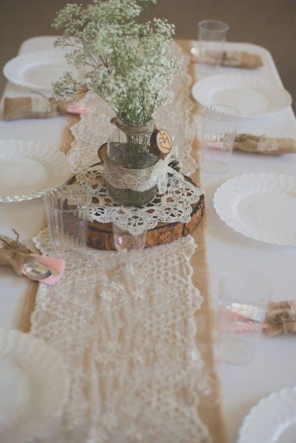 the table is set with white plates and flowers in a vase on top of it