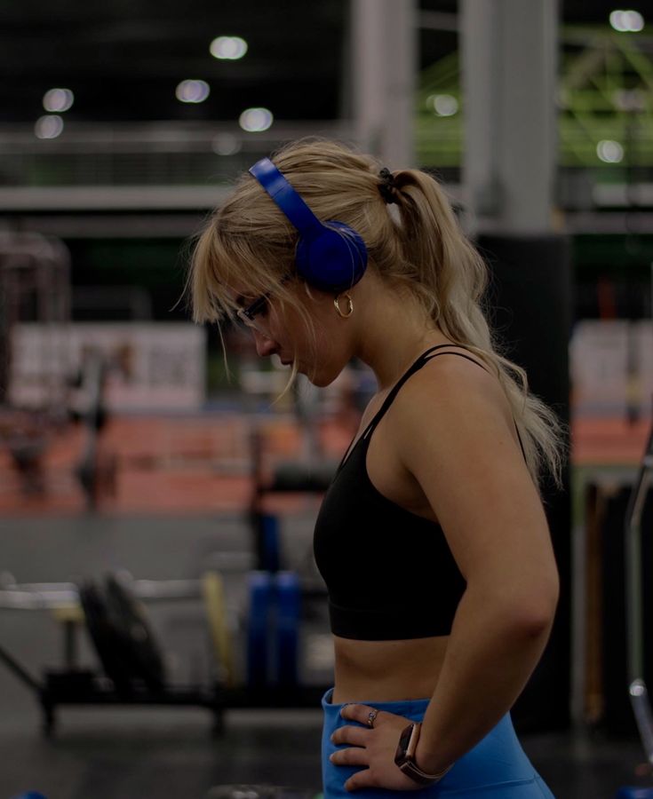 a woman with headphones standing in a gym