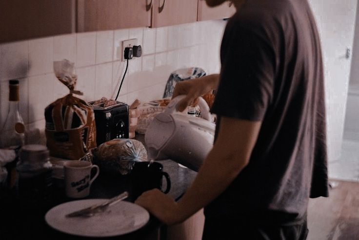 a man standing in front of a kitchen counter filled with dishes and coffee mugs