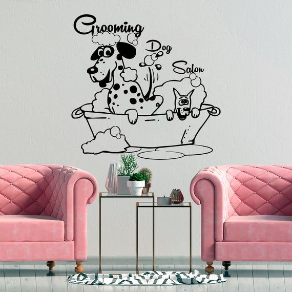 a living room with two pink couches and a dog wall decal on the wall