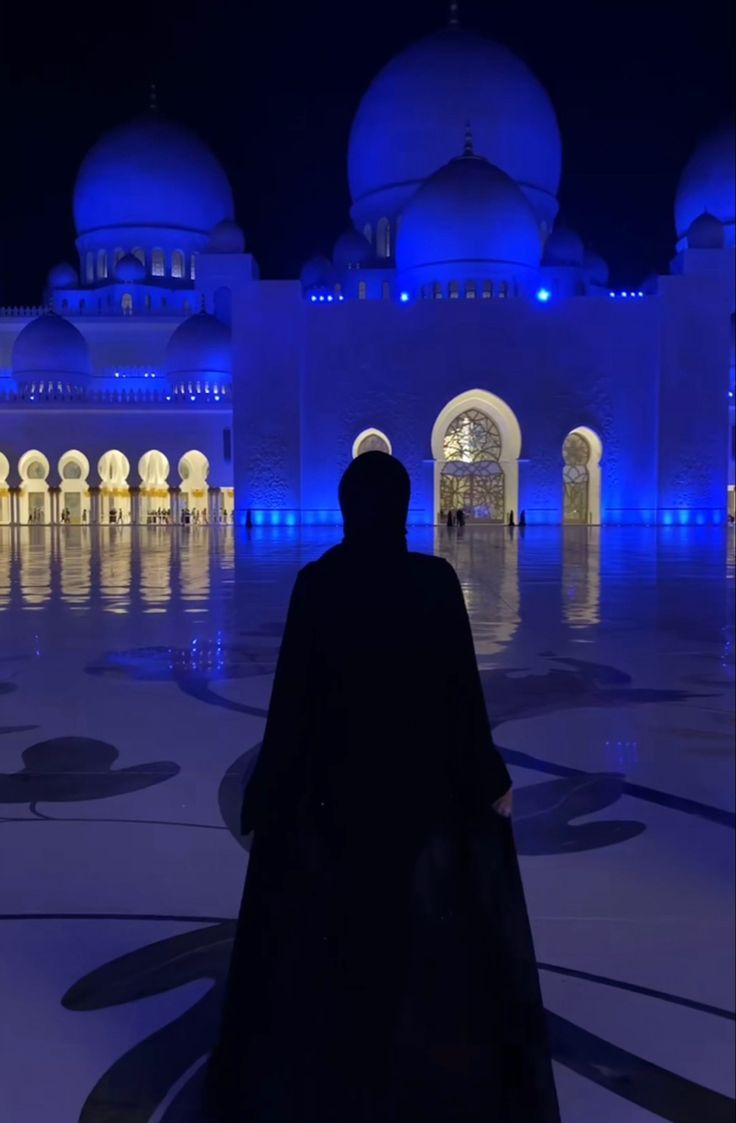 a man standing in front of a building with blue lights on it's walls