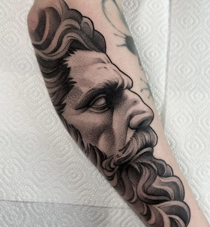 a man's arm with a black and white tattoo of a bearded face on it