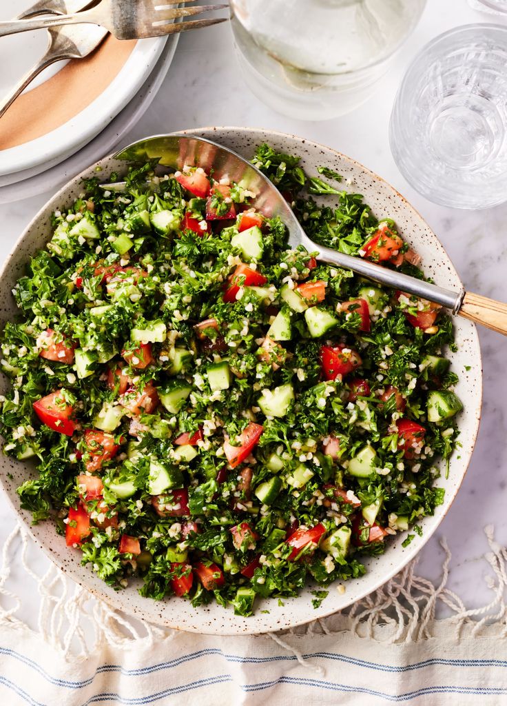 a bowl filled with chopped vegetables next to a glass of water and utensils