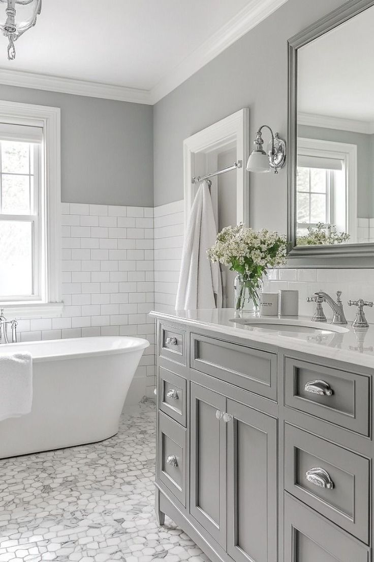 a white and gray bathroom with a tub, sink, mirror and window in it