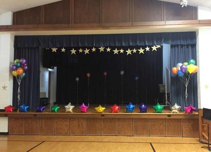 an empty room with balloons and stars on the wall, in front of a stage