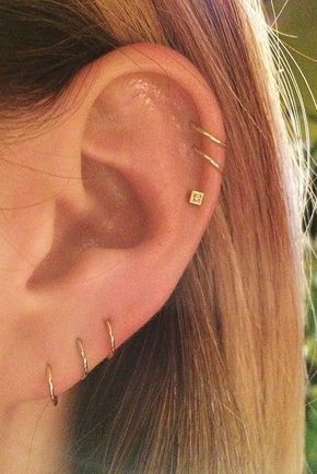 a close up of a person's ear with three different piercings on it