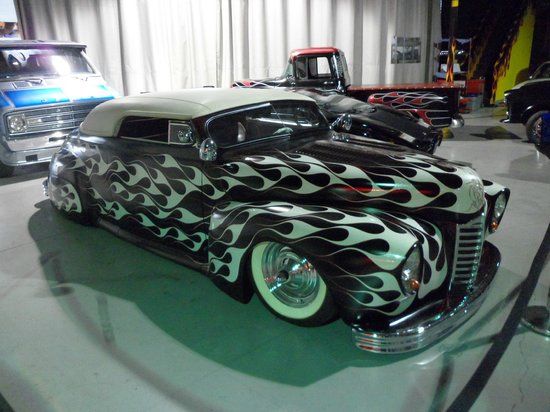 an old car with black and white flames on it's hood is parked in a garage