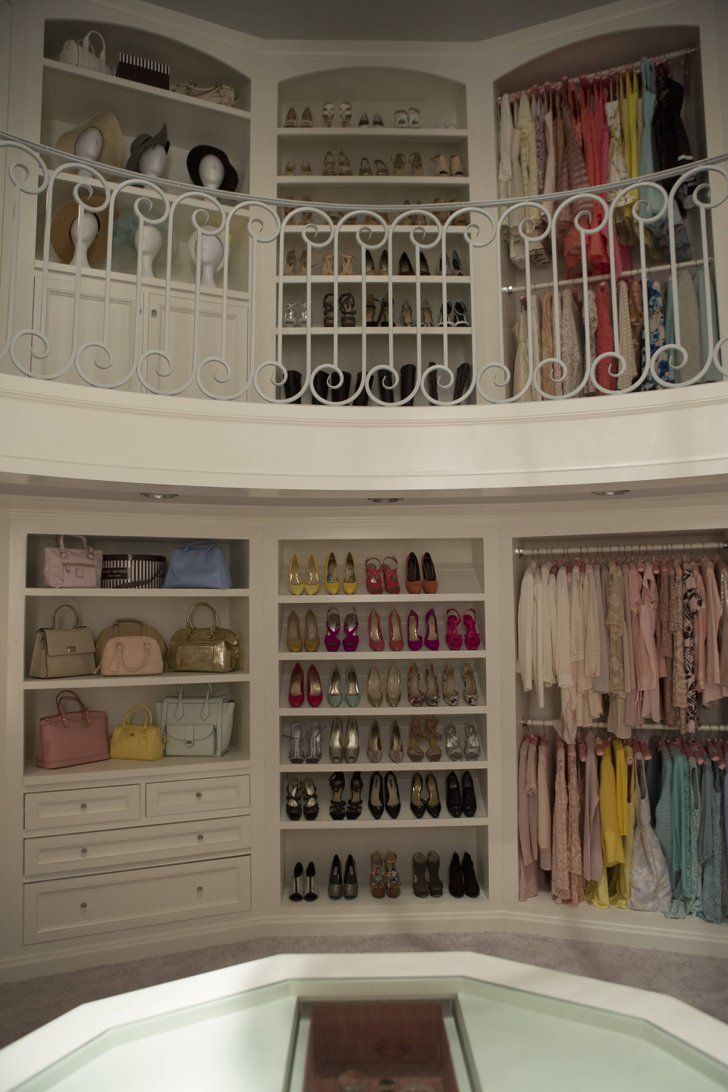 an organized closet with shoes, purses and handbags on the bottom shelf in front of a spiral staircase