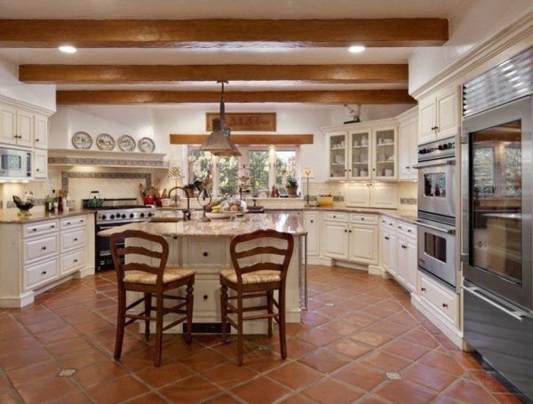 a large kitchen with white cabinets and tile flooring