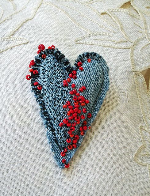 a blue heart with red beads on it sitting on a white cloth covered tablecloth