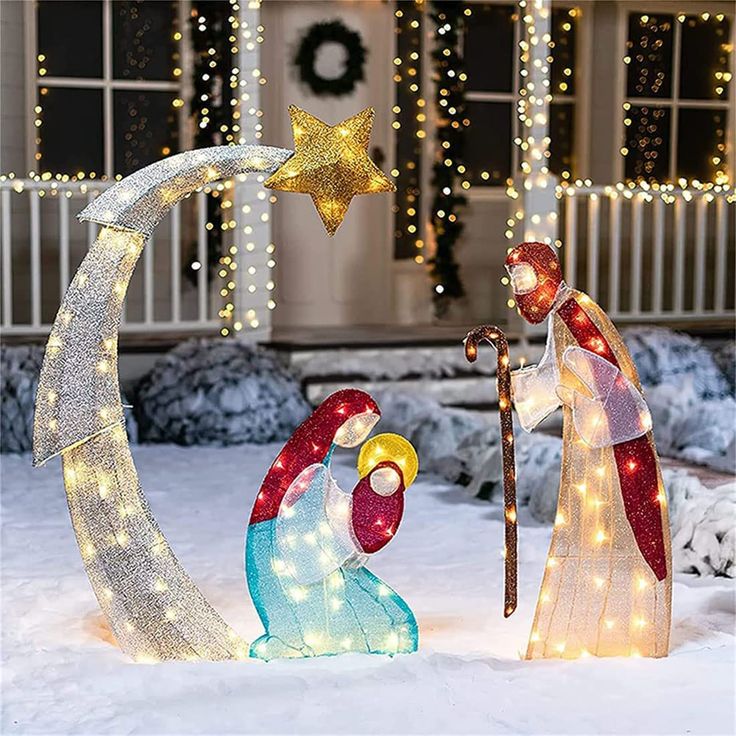 two nativity figurines in front of a house decorated with christmas lights and decorations