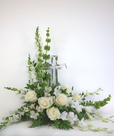 a cross with flowers and greenery in front of it