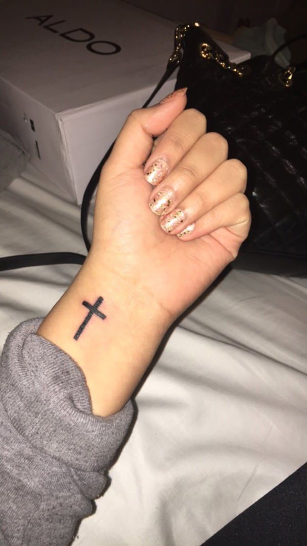 a woman's arm with a cross tattoo on it