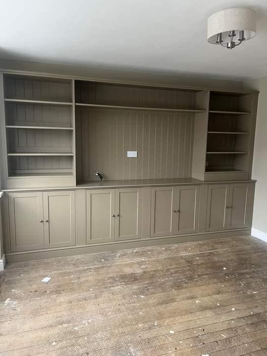 an empty living room with wooden floors and built in bookshelves