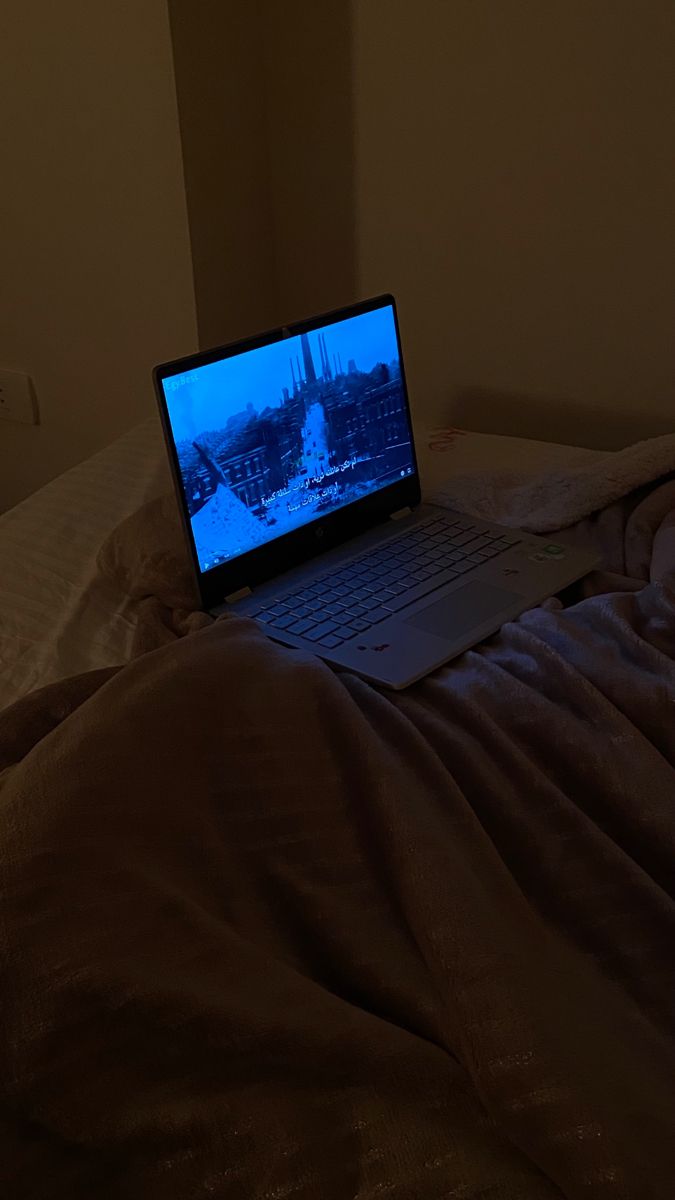 a laptop computer sitting on top of a bed in a room with no one around