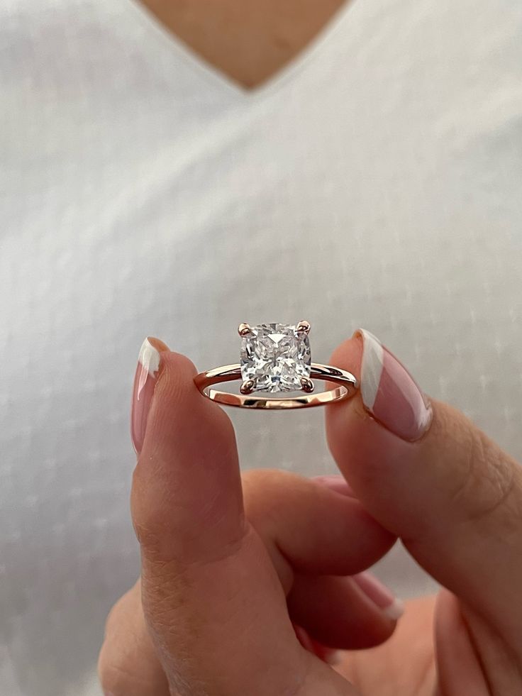 a woman's hand holding a ring with a diamond in the middle and white stripes on it