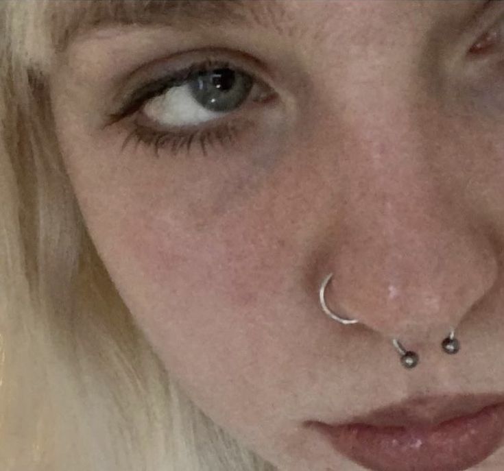 a close up of a person with a nose ring and piercing on it's nose