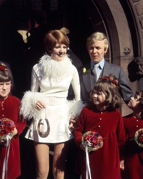 a woman in a white dress is standing with her children and two men behind her