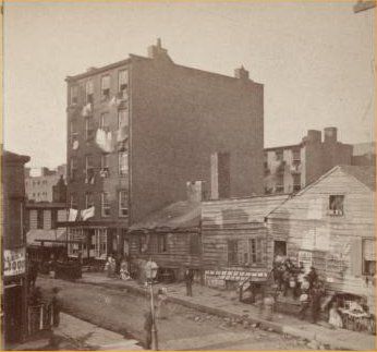 an old black and white photo of people on the street in front of some buildings