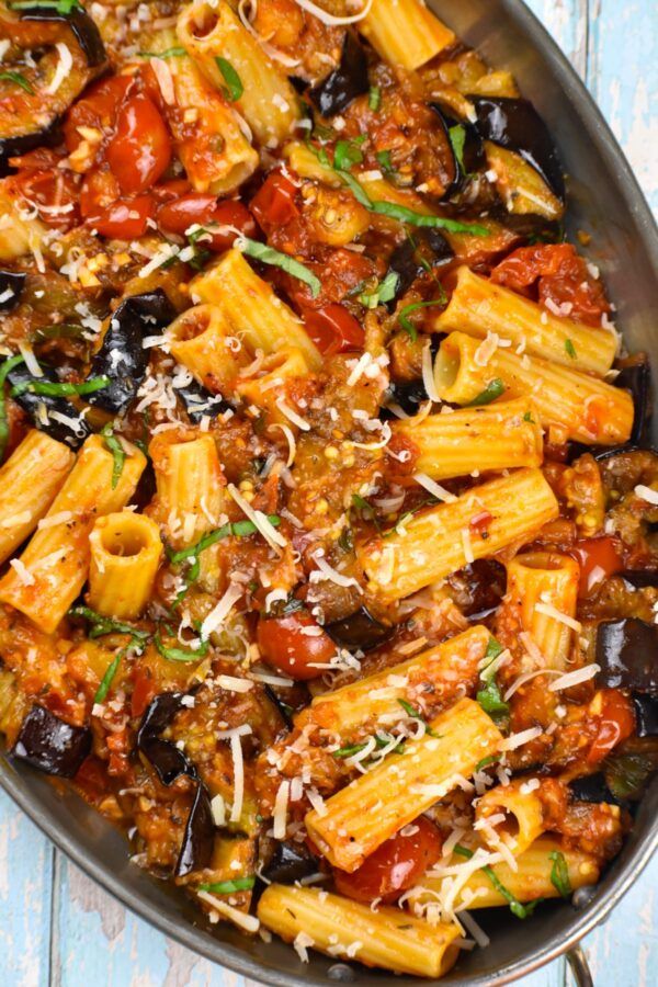 a skillet filled with pasta and sauce on top of a blue wooden table next to a