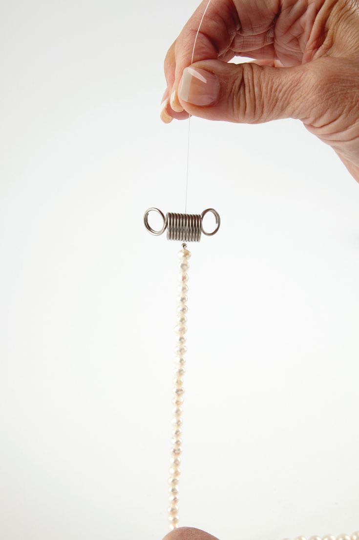 a hand holding a string with pearls attached to it