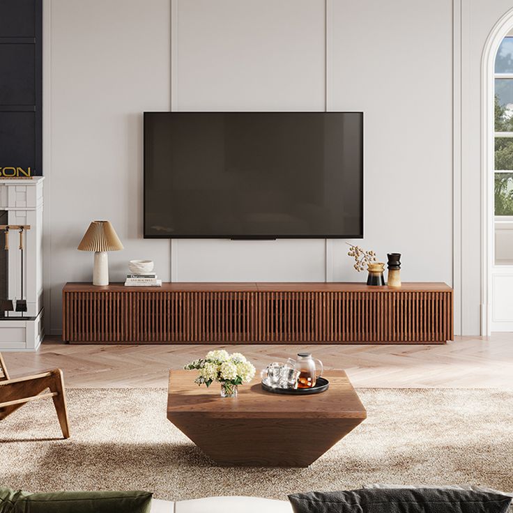 a living room with a large flat screen tv mounted on the wall next to a wooden coffee table