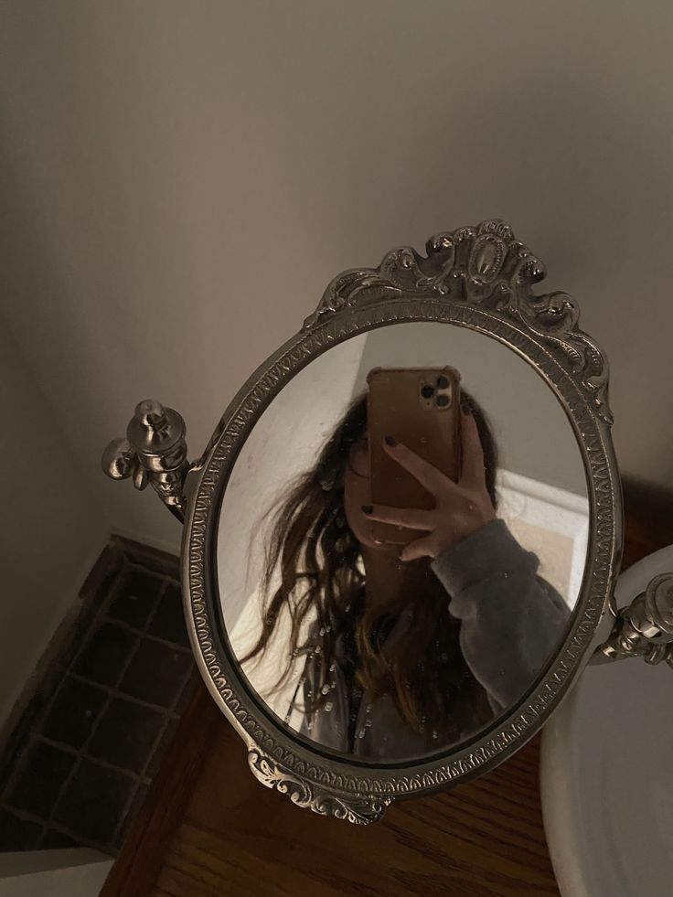 a woman taking a selfie in front of a mirror with her hair blowing back