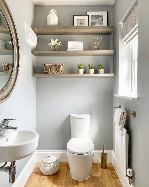 a white toilet sitting next to a sink in a bathroom under a large round mirror