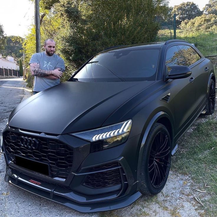 a man standing next to a black sports car