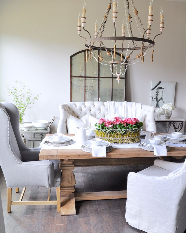 a dining room table with chairs, plates and flowers in a basket on top of it