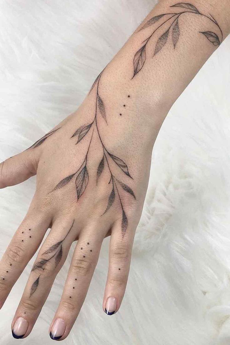 a woman's hand with a tattoo on it and some leaves in the middle