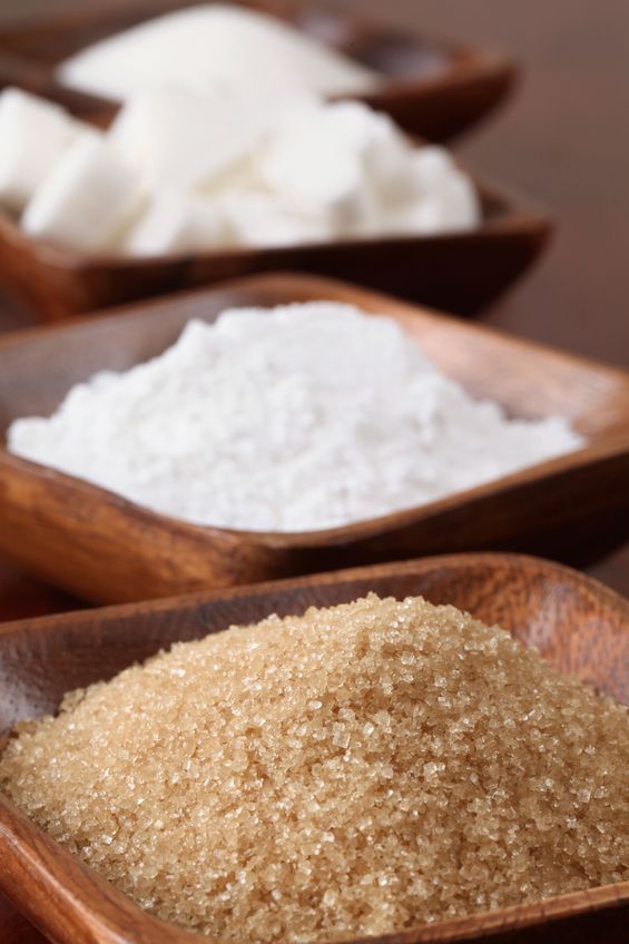 two wooden spoons filled with sugar on top of a table