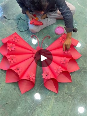 a man kneeling down next to red paper flowers