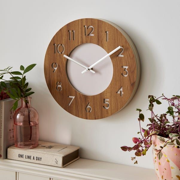 a wooden clock sitting on top of a white shelf next to a potted plant