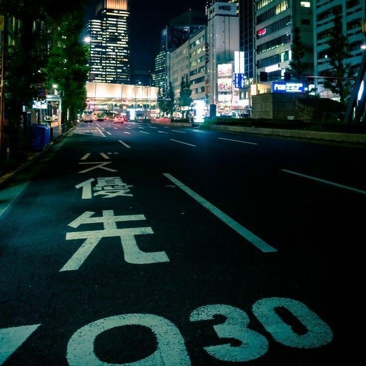 an empty city street at night with chinese characters painted on the road and buildings in the background