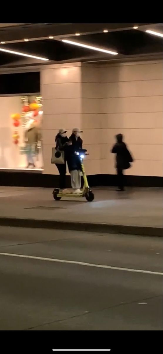 a person riding a scooter down a street at night