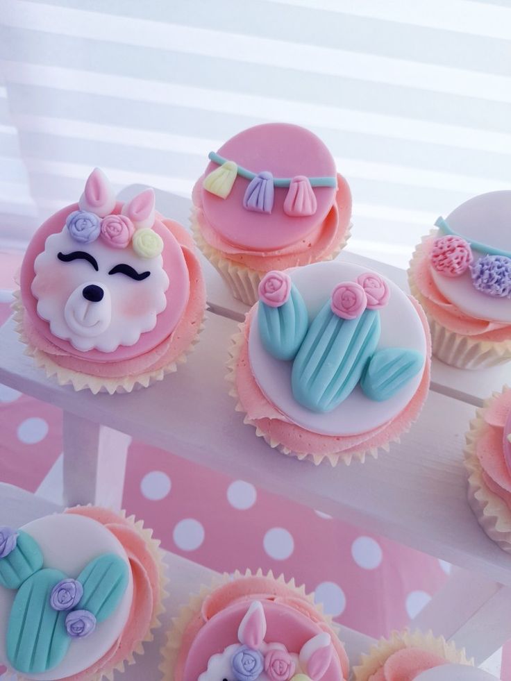 cupcakes decorated with pink and blue frosting are displayed on a white table